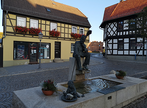 Marktbrunnen mit sitzender Statue eines Bergmanns, der sich nachdenklich übers Kinn streicht